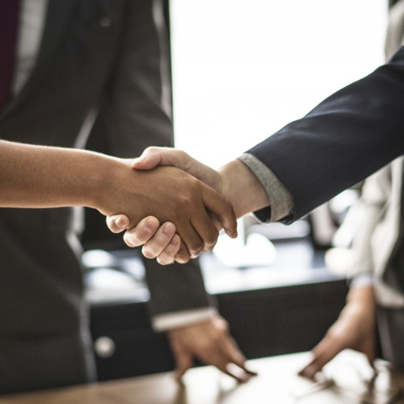 An illustration of a business man and a business woman shaking hands in partnership