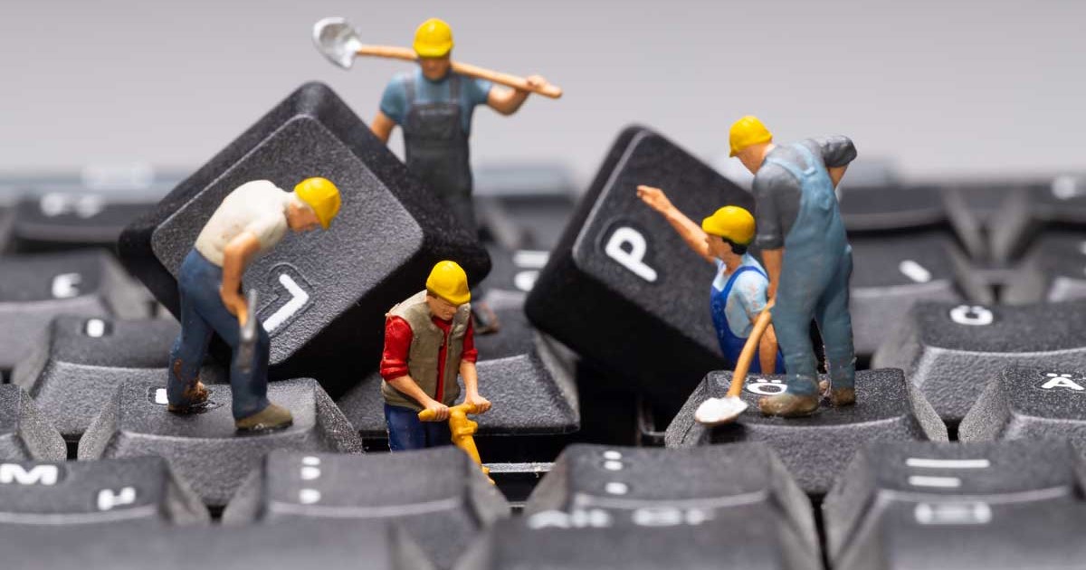 Team of mini figurines repairing a keyboard